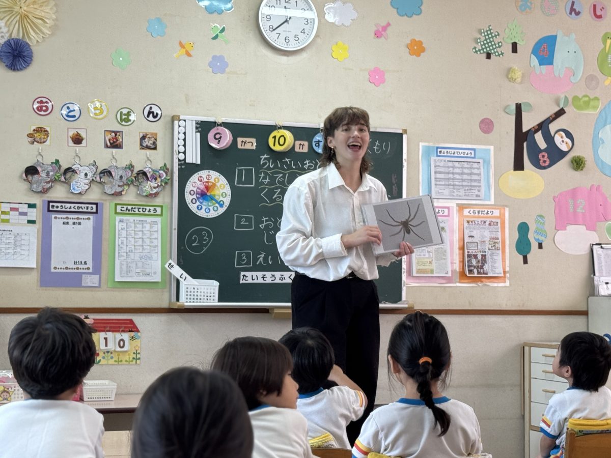絵カードを見せながら、子どもたちに英語で話しかける外国人講師
