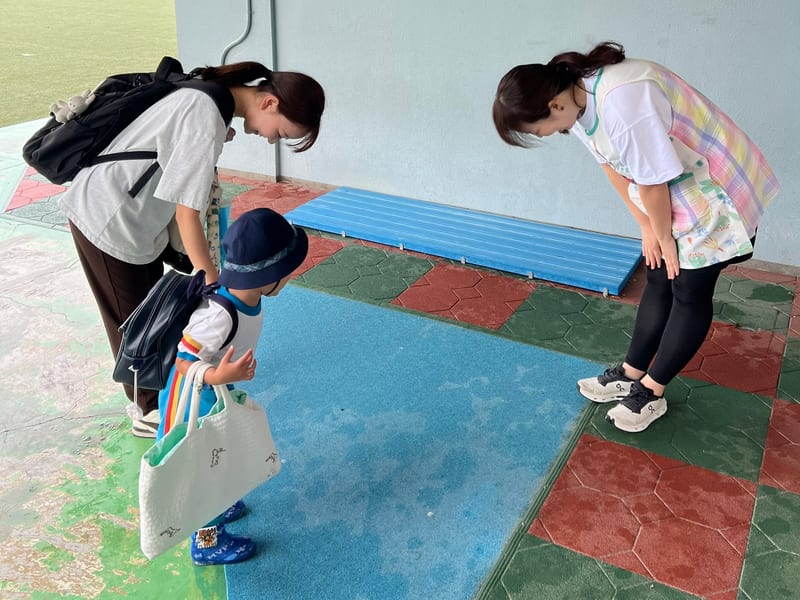 A child and parent greeting the teacher in the morning