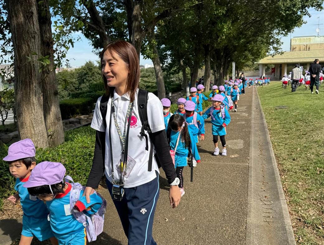 Children walking a tree-lined path with their teacher