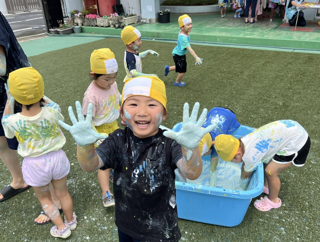 Children laughing with paint on their hands and faces