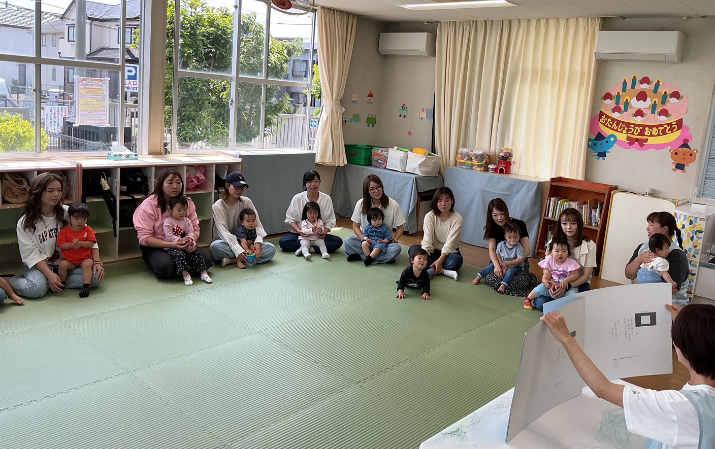 Parents and children listening to a teacher together at Piyopiyo