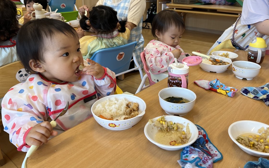Children eating their school lunch with a spoon by themselves