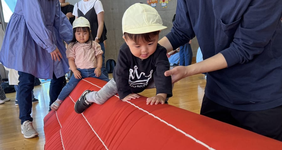 A child exercising in the hall, watched by parents and teachers
