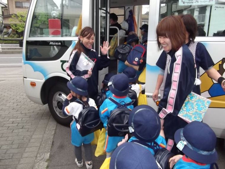A staff member welcoming children onto the school bus