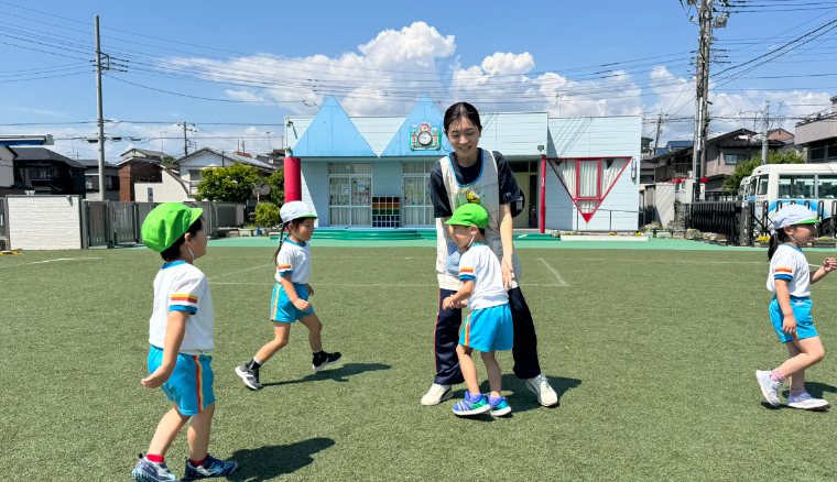 A teacher beside a child in the playground under a blue sky